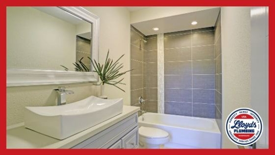 A bathroom with a porcelain sink, mirror, and bath shower combo